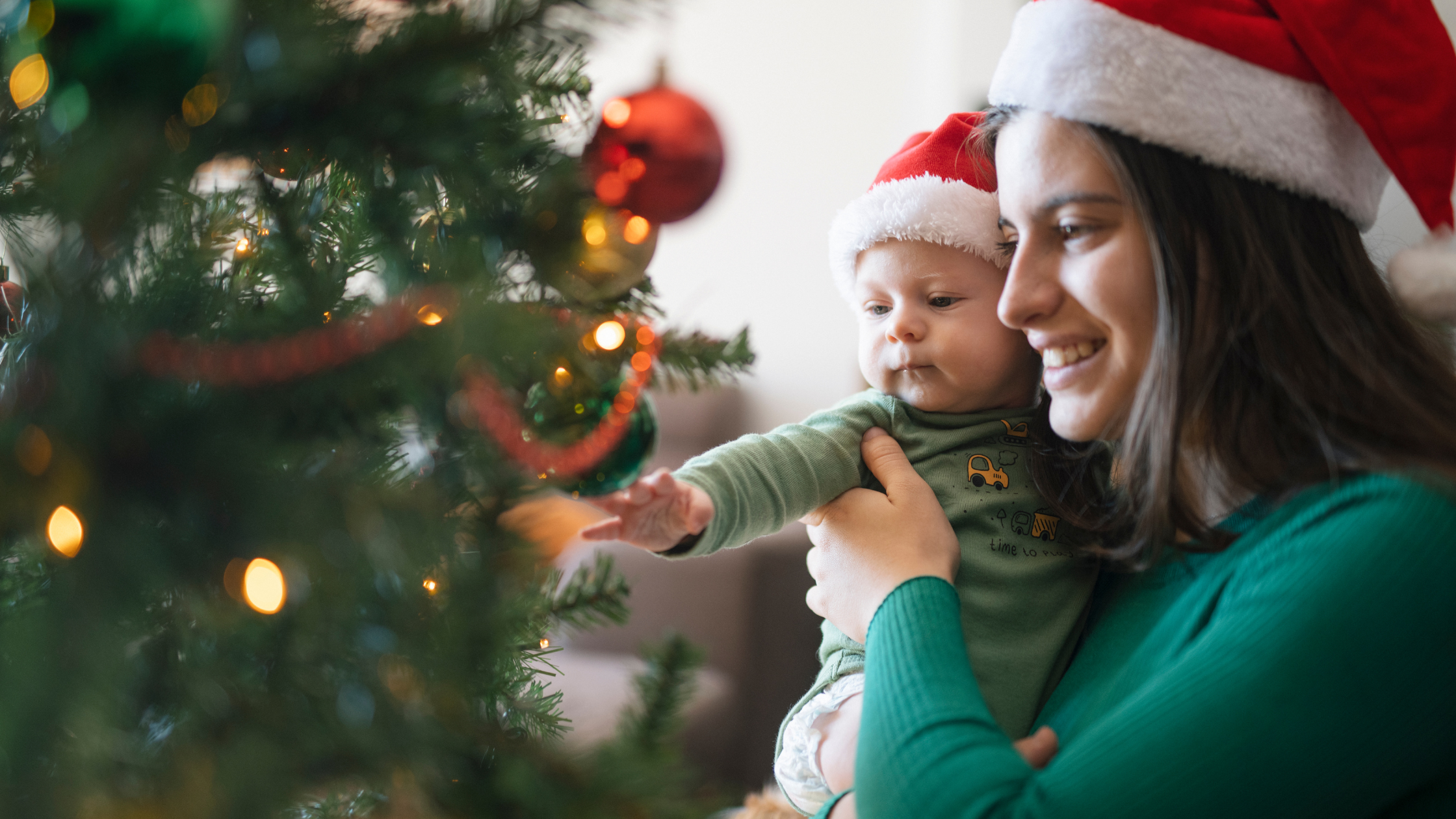 Madre decorando árbol navidad con bebe